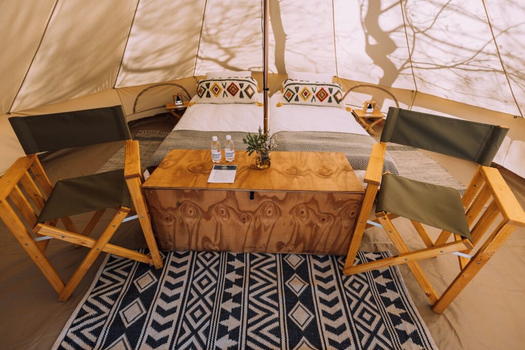 Interior of glamping tent with two full-size single beds and hotel linen