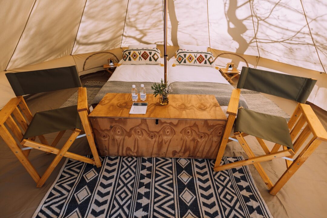 Interior of glamping tent with two full-size single beds and hotel linen